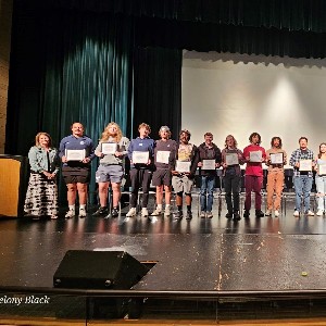 AVID students holding their certificates on stage with Ms. Tews